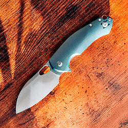 Folding knife with a green handle on a wooden surface