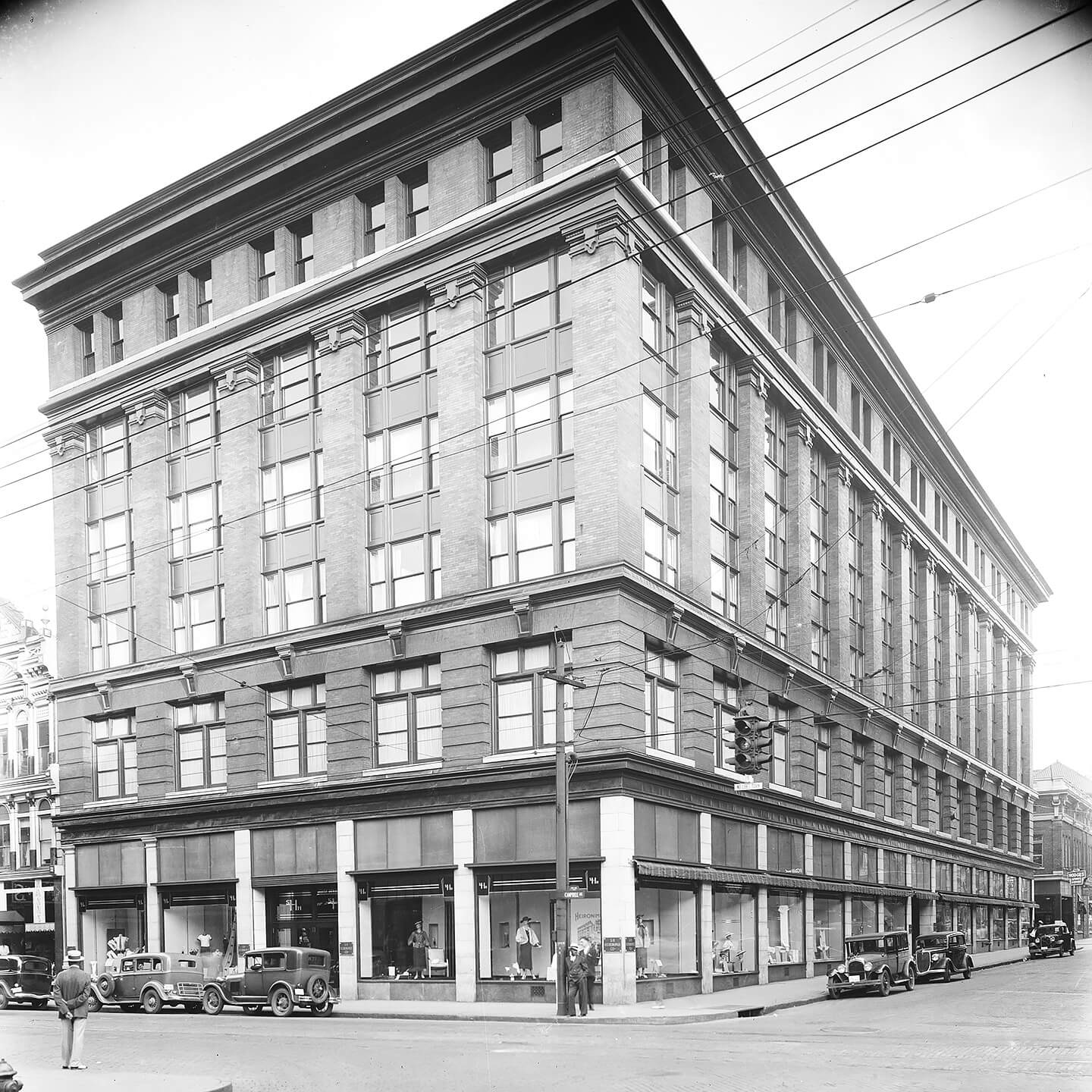 Vintage black and white photo of the Heironimus Store with cars parked in front