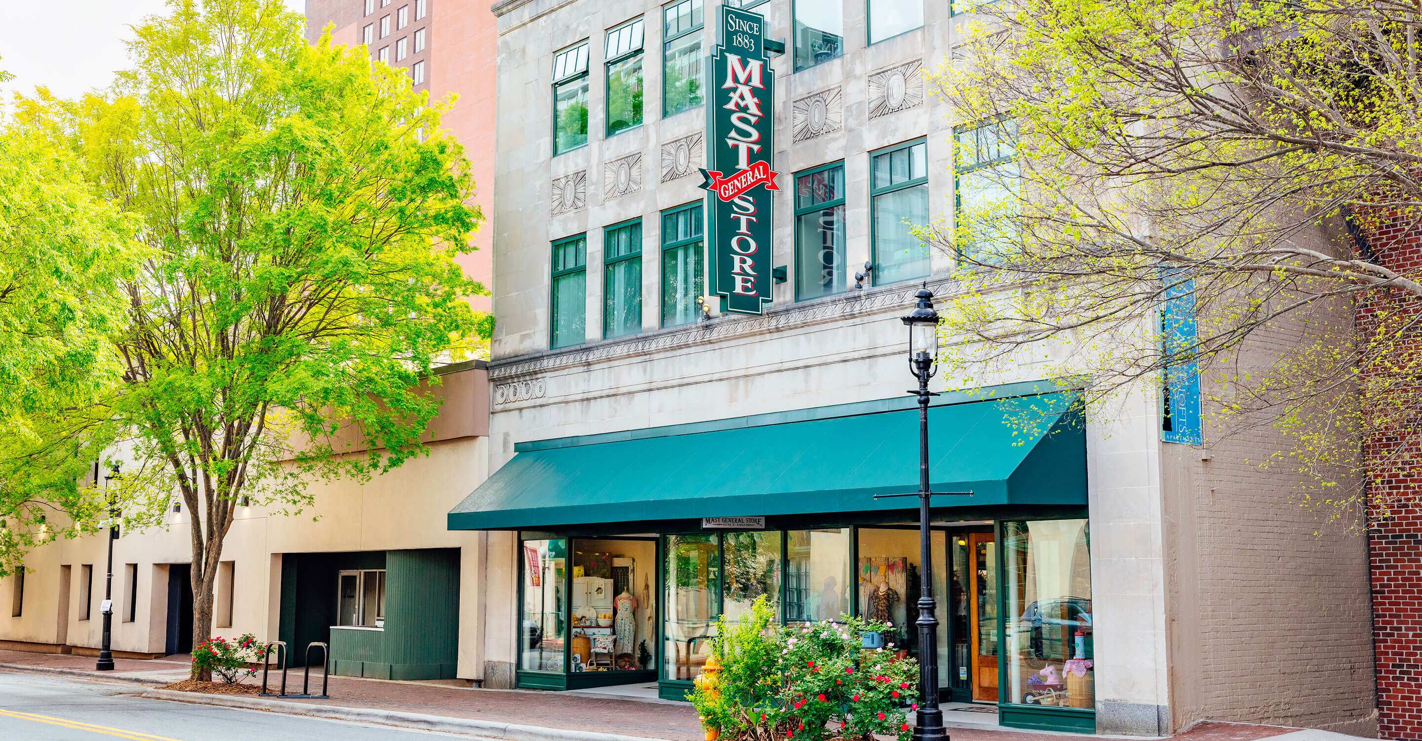 Street view of the Winston-Salem Mast Store with a green awning and blade sign